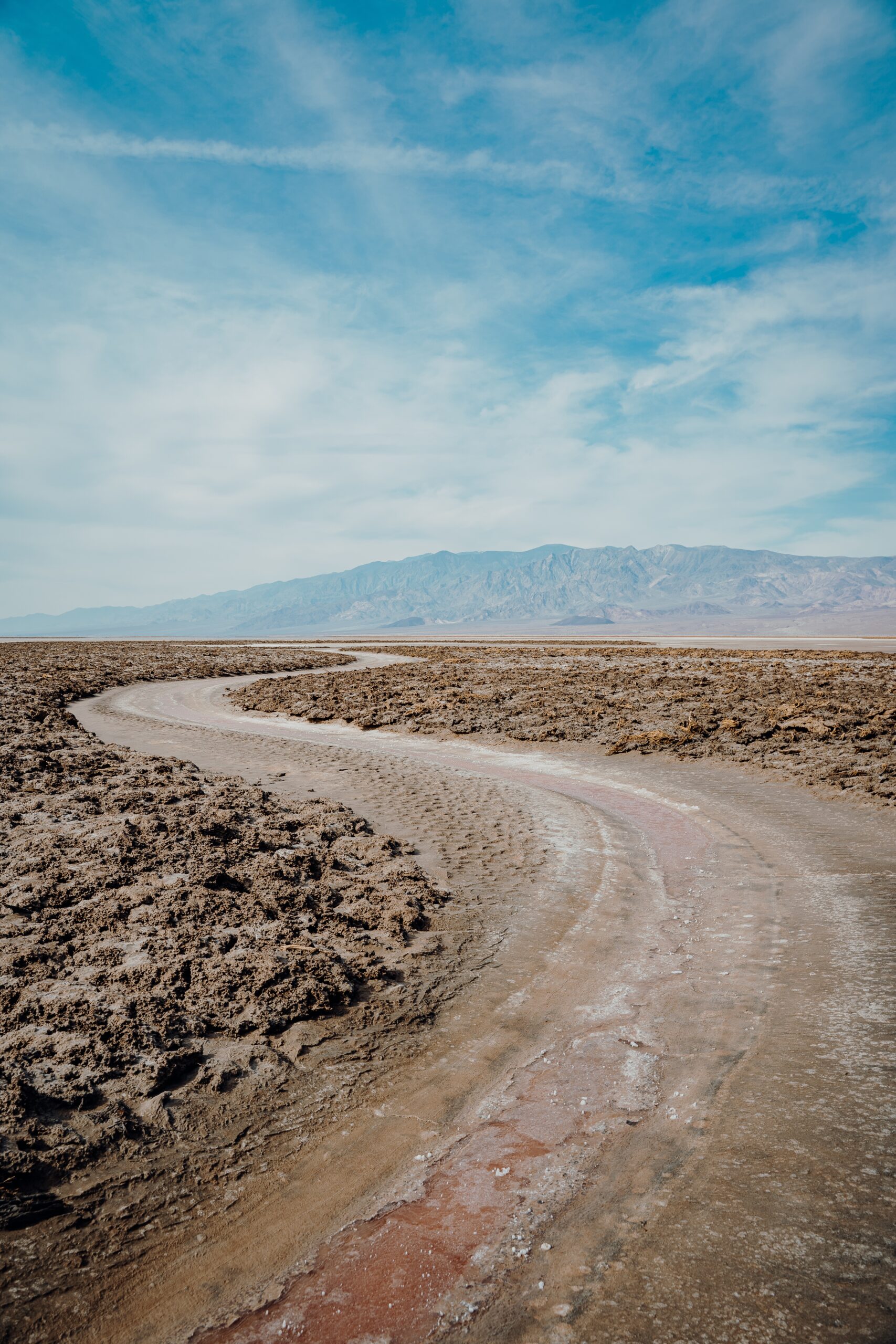 A vertical shot of a winding road surrounded by a sandy ground